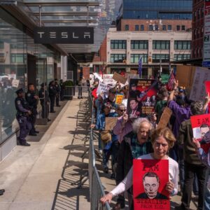 New York Police Department (NYPD) officers stand guard as protesters demonstrate during a Tesla Takedown rally outside a Tesla showroom in New York
