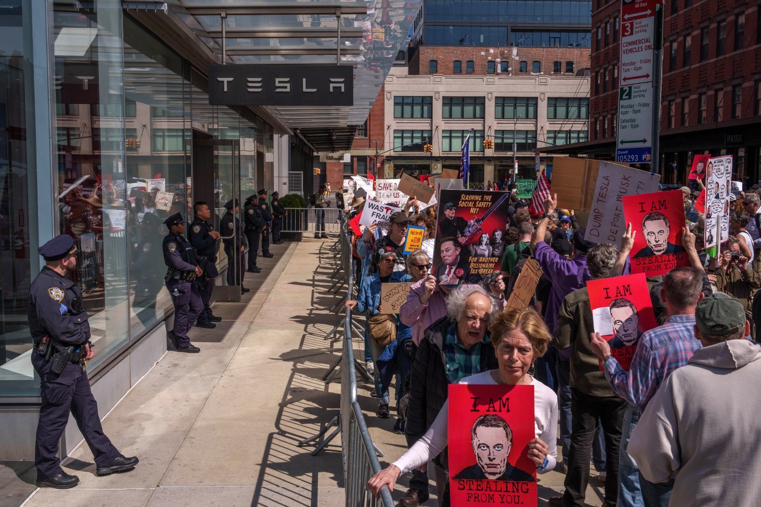New York Police Department (NYPD) officers stand guard as protesters demonstrate during a Tesla Takedown rally outside a Tesla showroom in New York