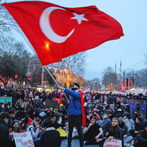 University students wave flags and protest next to riot police in Instanbul, Turkey