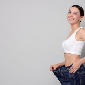Wanita muda yang bahagia hasil penurunan berat badan longgar
