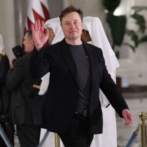 Elon Musk waves as he arrives for a state dinner at the Lusail Palace on May 14, 2025, in Doha, Qatar.